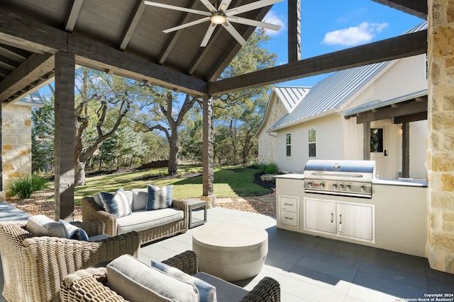 view of patio with area for grilling, an outdoor living space, ceiling fan, and exterior kitchen