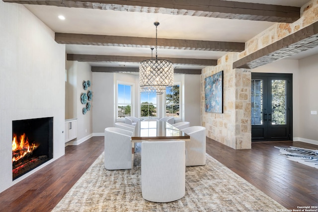 dining room with a large fireplace, a chandelier, beam ceiling, french doors, and dark wood-type flooring