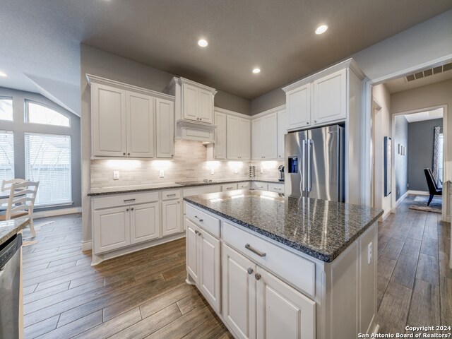 kitchen with a center island, white cabinetry, dark stone counters, dark hardwood / wood-style flooring, and stainless steel appliances