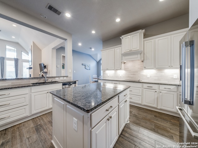 kitchen with a kitchen island, lofted ceiling, dark hardwood / wood-style floors, dark stone counters, and white cabinets