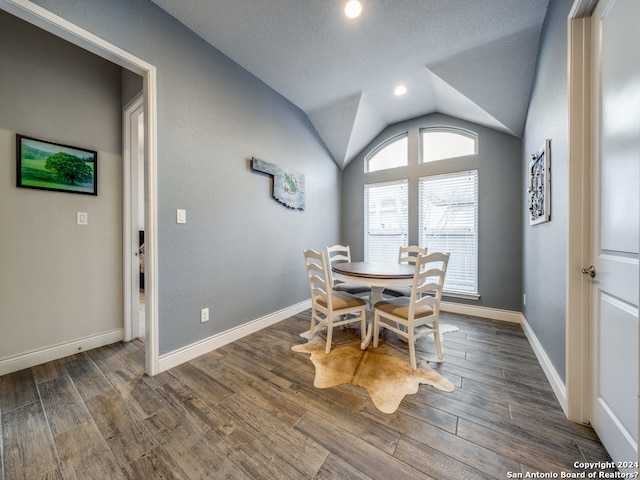 dining area featuring dark hardwood / wood-style floors, vaulted ceiling, and a textured ceiling