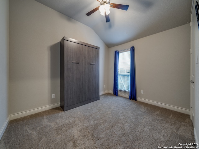 unfurnished bedroom featuring a closet, ceiling fan, dark carpet, and vaulted ceiling