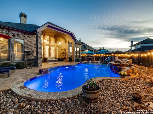 pool at dusk featuring a patio area and pool water feature