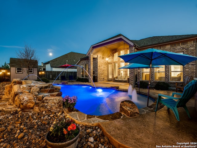 view of swimming pool with a patio, a storage shed, and pool water feature