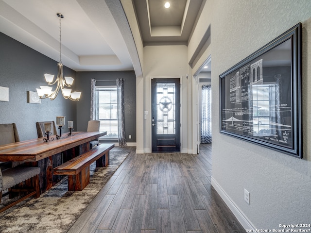 entryway featuring dark hardwood / wood-style floors, a tray ceiling, and an inviting chandelier