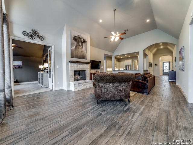 living room featuring high vaulted ceiling, dark hardwood / wood-style floors, ceiling fan, and a fireplace