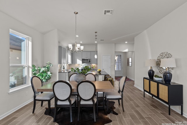 dining area with dark hardwood / wood-style flooring, an inviting chandelier, and sink