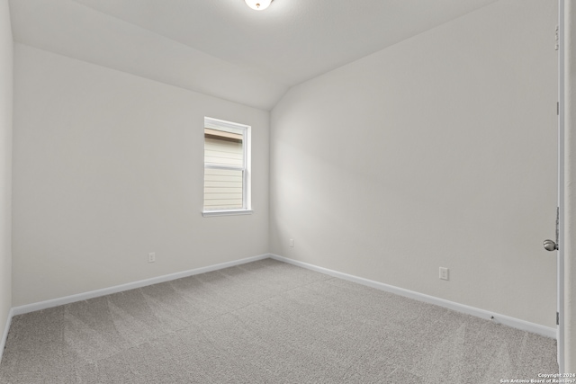 carpeted spare room featuring vaulted ceiling