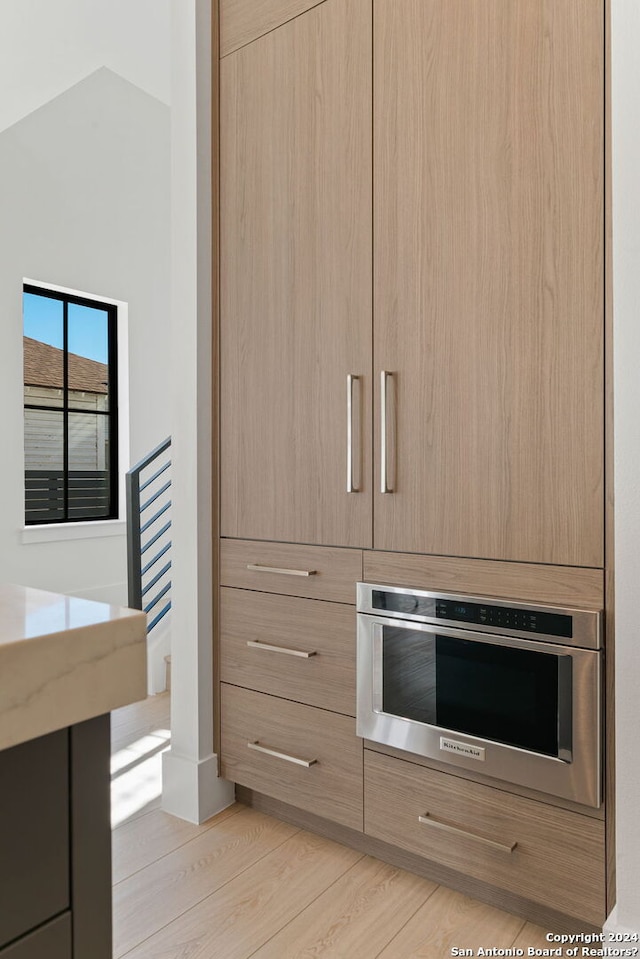 kitchen featuring light brown cabinets, light wood-type flooring, and oven