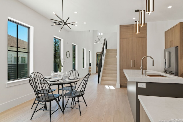 kitchen with high quality fridge, hanging light fixtures, light hardwood / wood-style floors, and a notable chandelier