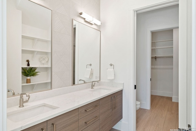 bathroom with toilet, hardwood / wood-style floors, dual vanity, and built in features