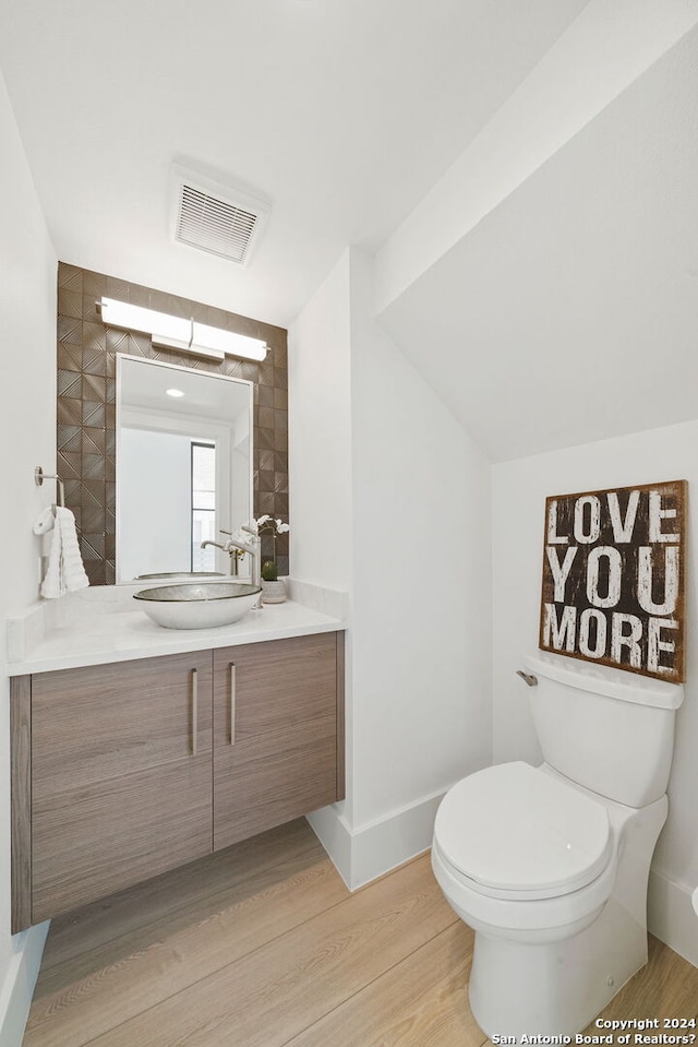 bathroom with hardwood / wood-style flooring, tile walls, toilet, and vanity