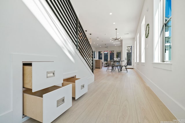 corridor with a notable chandelier and light hardwood / wood-style floors