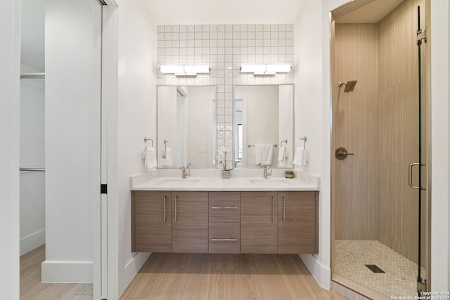 bathroom with hardwood / wood-style flooring, double sink vanity, and walk in shower