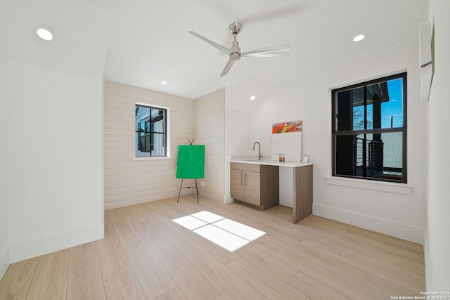 unfurnished bedroom featuring multiple windows, ceiling fan, sink, and light wood-type flooring