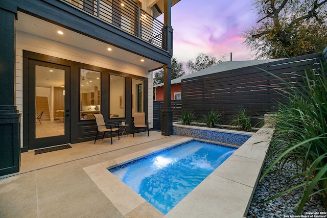 pool at dusk featuring a patio