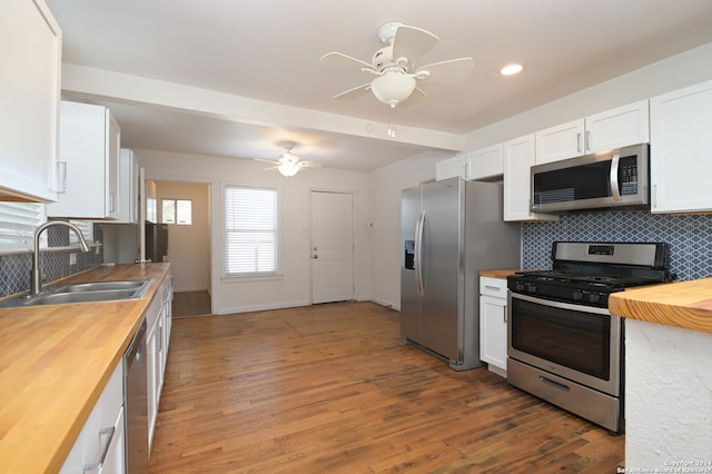 kitchen featuring backsplash, appliances with stainless steel finishes, light hardwood / wood-style floors, and ceiling fan