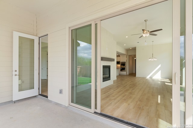 unfurnished sunroom featuring ceiling fan and a fireplace