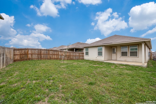 back of property with a lawn and a patio