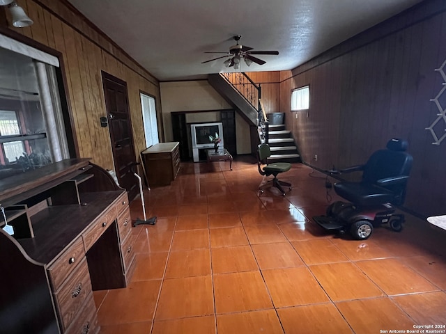 interior space featuring light tile floors, wood walls, and ceiling fan