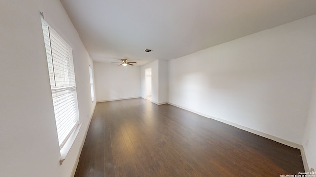 unfurnished room featuring ceiling fan, dark wood-type flooring, and plenty of natural light