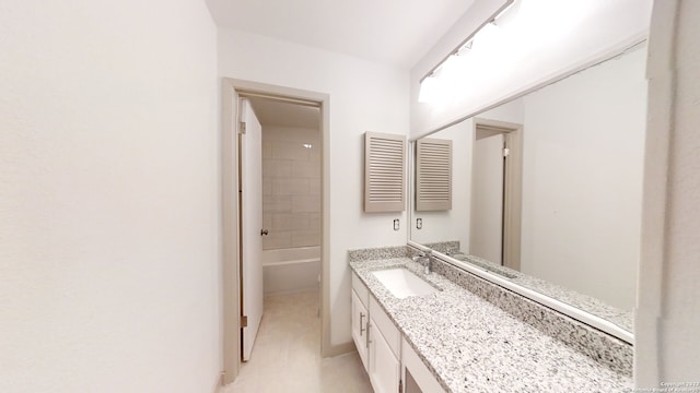 bathroom with large vanity and tiled shower / bath