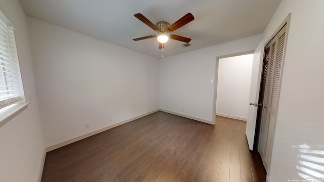 unfurnished room featuring dark wood-type flooring and ceiling fan