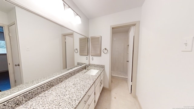 bathroom with a tile shower, vanity, and wood-type flooring