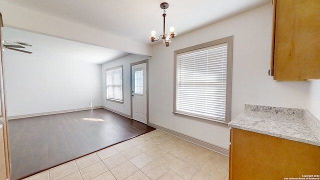 doorway to outside with light tile flooring and ceiling fan with notable chandelier