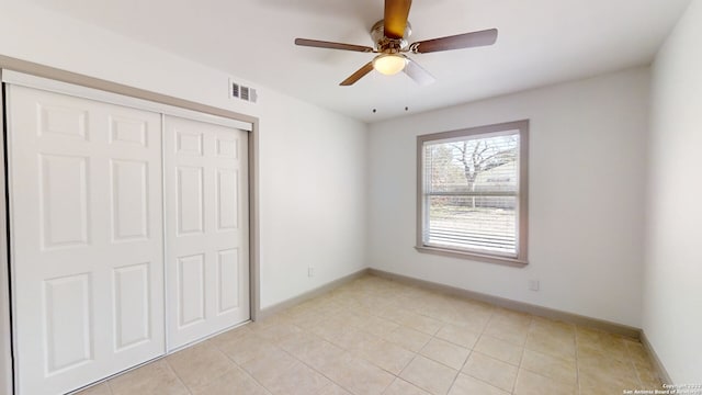 unfurnished bedroom with light tile floors, a closet, and ceiling fan