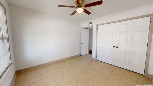 unfurnished bedroom featuring light tile floors, a closet, and ceiling fan