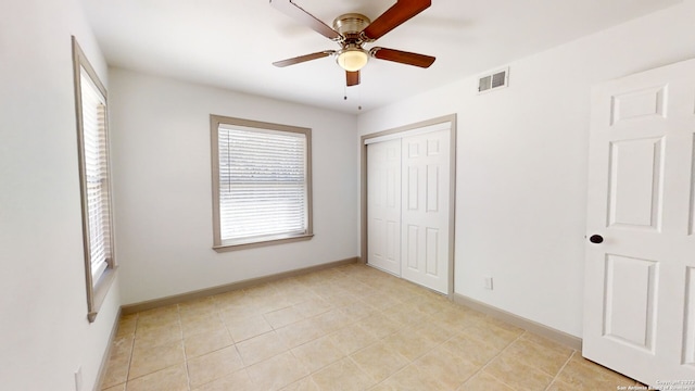 unfurnished bedroom with ceiling fan, light tile floors, and a closet