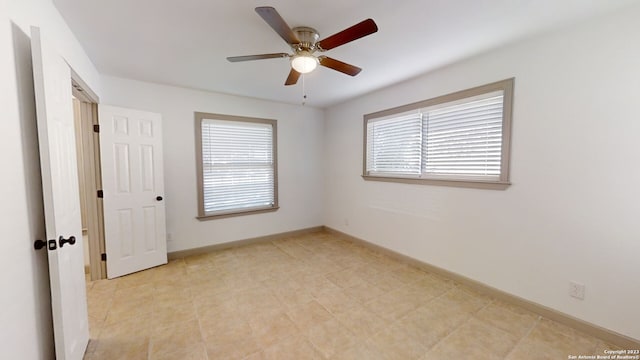 tiled empty room featuring ceiling fan and plenty of natural light