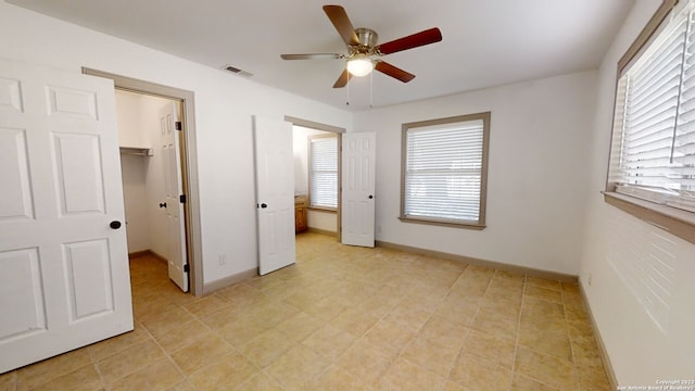 unfurnished bedroom featuring light tile floors, a spacious closet, a closet, and ceiling fan