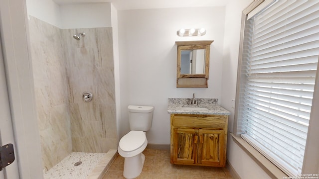 bathroom featuring vanity, tile flooring, toilet, and tiled shower