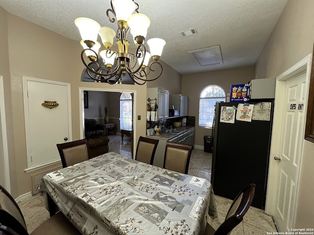 dining area with a notable chandelier, light tile floors, and a textured ceiling