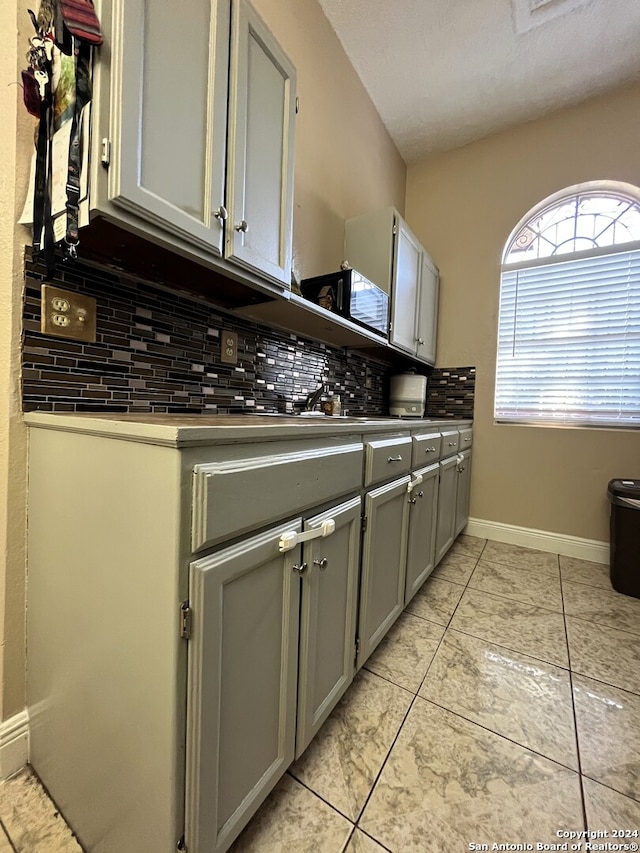 kitchen with tasteful backsplash, gray cabinets, and light tile floors