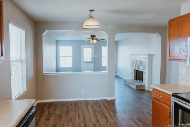 kitchen with ceiling fan, a fireplace, dark wood-type flooring, and hanging light fixtures