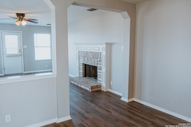 interior space featuring a brick fireplace, ceiling fan, and dark hardwood / wood-style floors