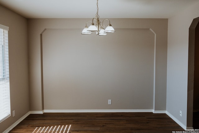 spare room with dark hardwood / wood-style flooring, an inviting chandelier, and plenty of natural light