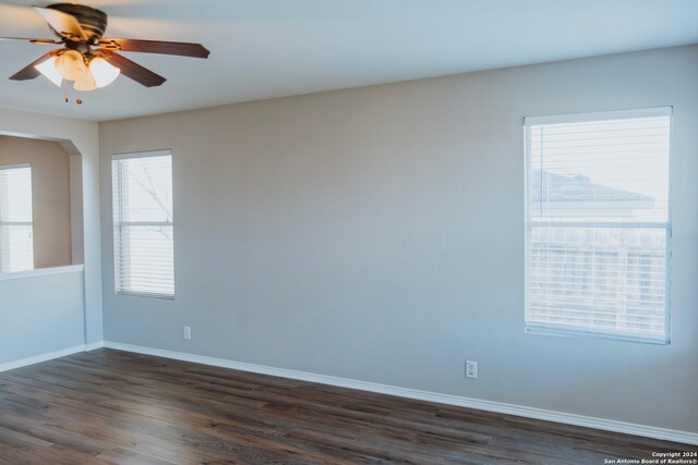 unfurnished room with dark hardwood / wood-style floors, ceiling fan, and a healthy amount of sunlight