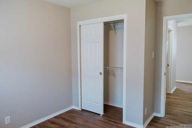 unfurnished bedroom featuring a closet and dark wood-type flooring