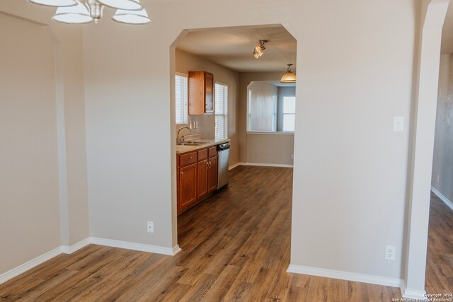 kitchen with hanging light fixtures, dark hardwood / wood-style floors, sink, a chandelier, and dishwasher