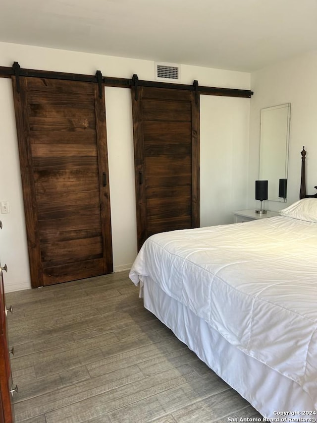 bedroom with a barn door and hardwood / wood-style flooring