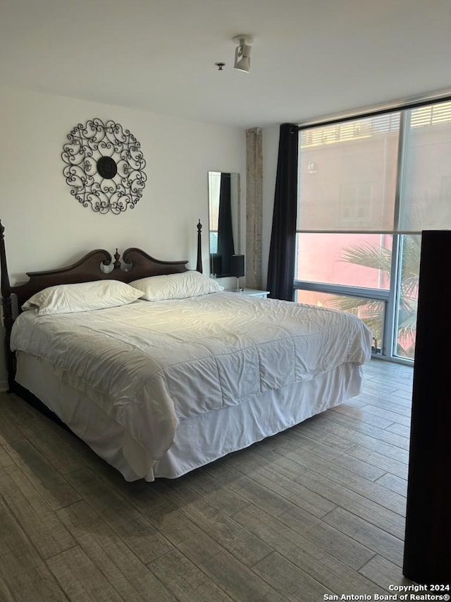 bedroom with dark hardwood / wood-style floors and a wall of windows