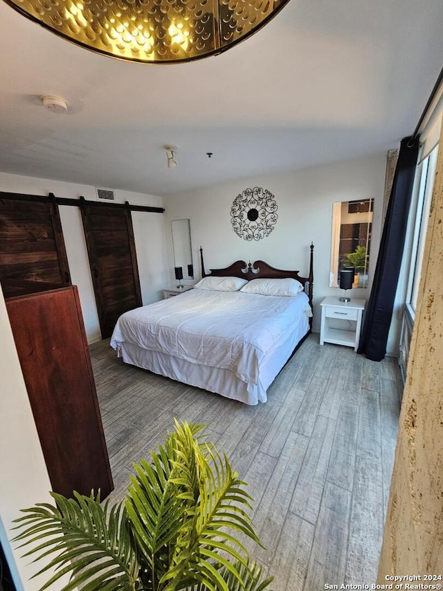 bedroom with a barn door and dark wood-type flooring