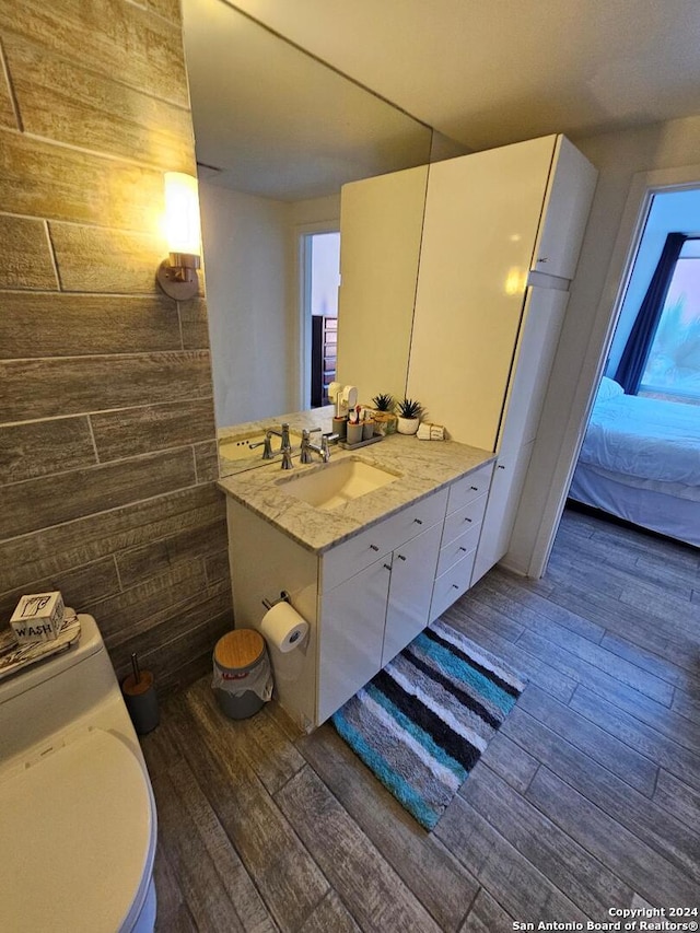 bathroom featuring wooden walls, toilet, hardwood / wood-style floors, and vanity