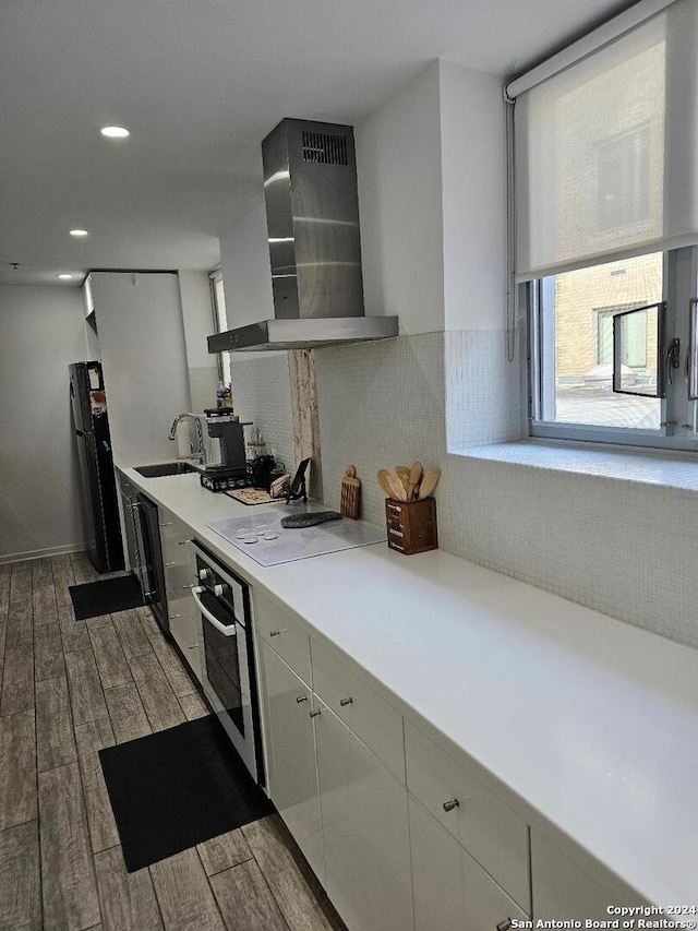 kitchen featuring light hardwood / wood-style floors, sink, white electric stovetop, stainless steel oven, and wall chimney range hood