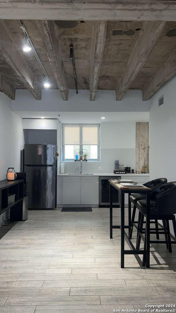 interior space with sink, light wood-type flooring, and wine cooler