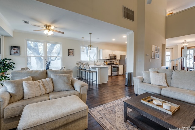 living room with ceiling fan, dark wood-type flooring, sink, and crown molding